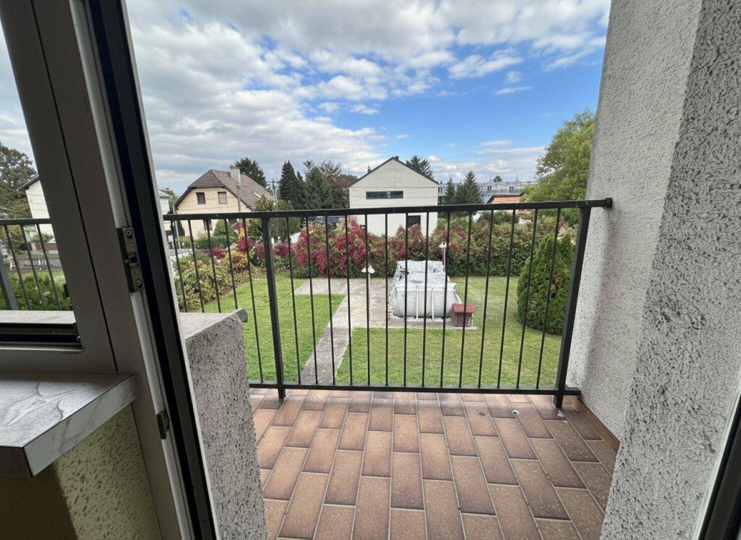 Balkon mit Fliesenboden und Metallgeländer, bietet einen weiten Blick über den Garten und die Umgebung.