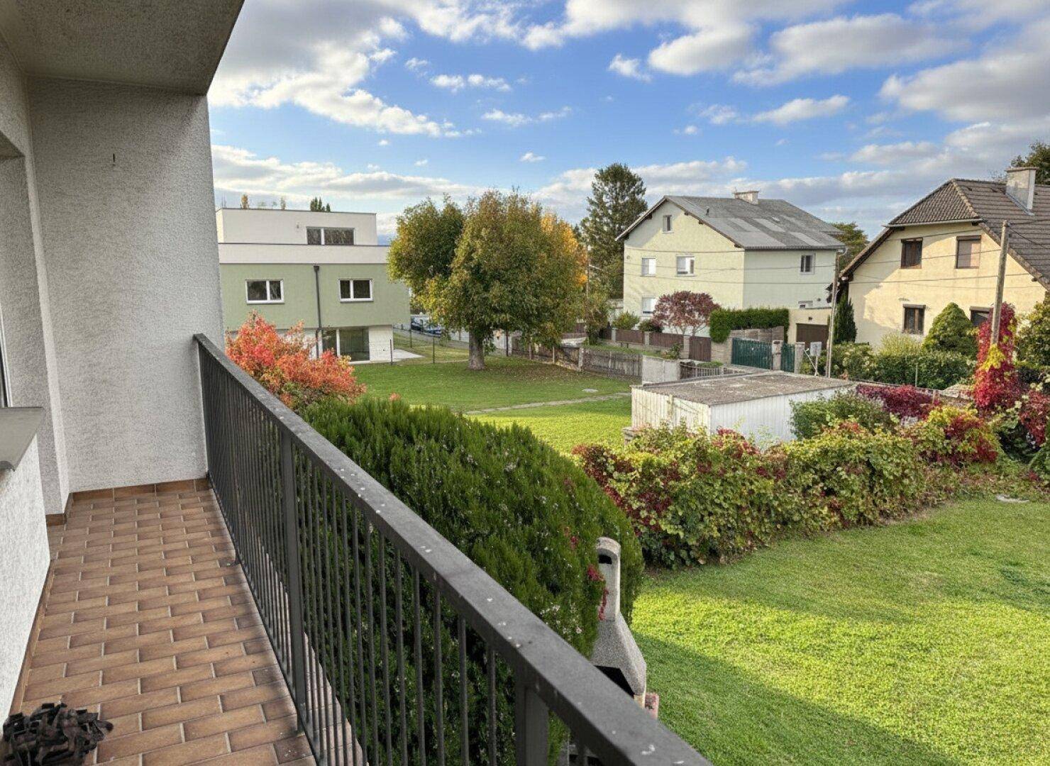 Balkon mit Fliesenboden und Metallgeländer, bietet einen weiten Blick über den Garten und die Umgebung.