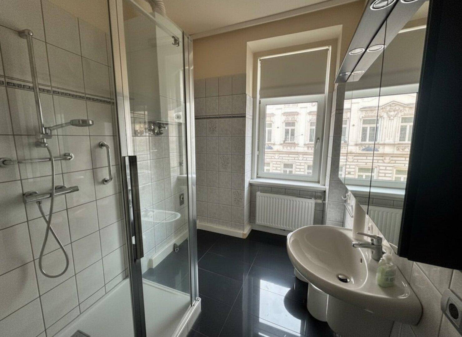 Modernes Badezimmer mit Duschkabine, Waschbecken, Spiegelschrank und Fenster.