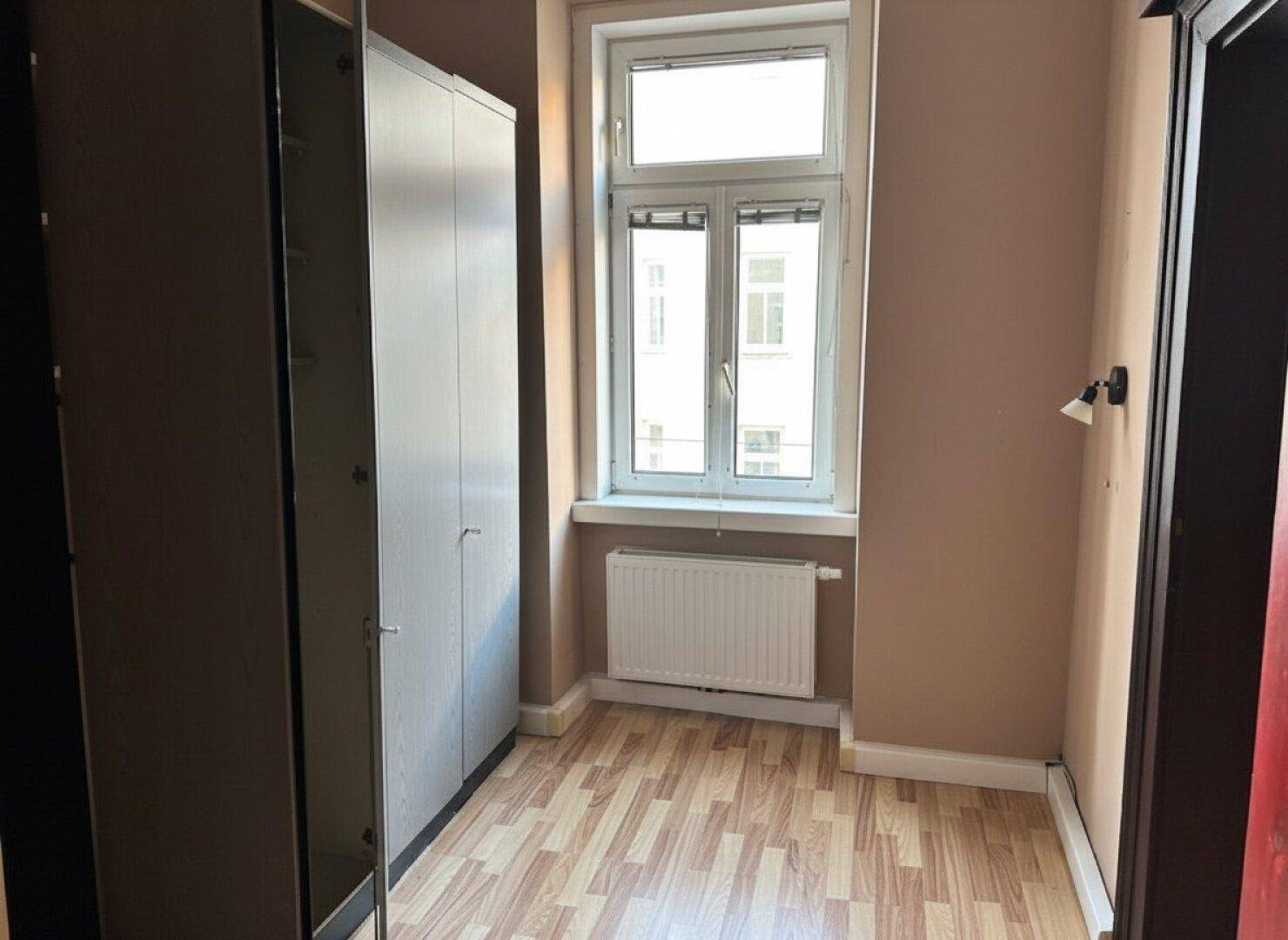 Schlafzimmer mit Laminatboden, hellbraunen Wänden und einem großen Kleiderschrank.