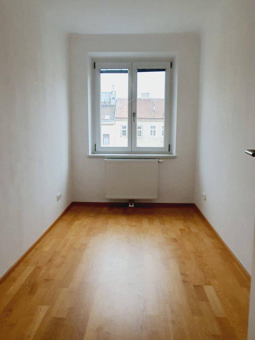 Kleiner, heller Raum mit Fenster und Holzboden, ideal als Schlaf- oder Arbeitszimmer.