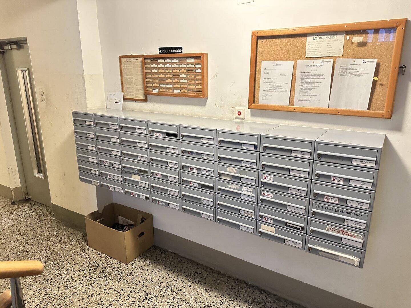 Eingangsbereich mit vielen Briefkästen, einer Pinnwand und Hinweisschildern.