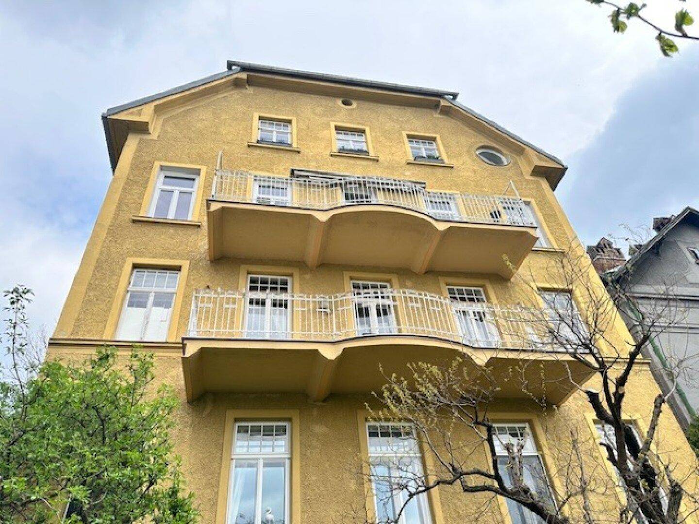 Historisches Gebäude mit gelber Fassade, mehreren Balkonen und traditioneller Architektur.