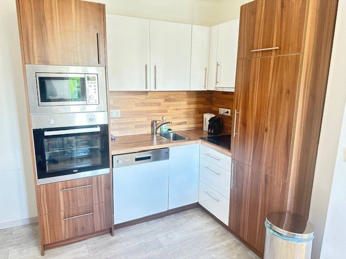 Moderne Einbauküche mit Holz- und weißen Fronten, ausgestattet mit Backofen und Mikrowelle.
