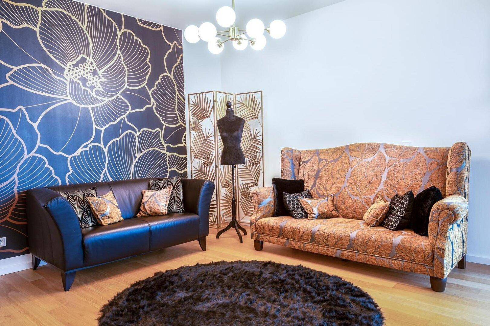 Gemütliches Wohnzimmer mit floraler Tapete, zwei Sofas und einem runden Teppich.