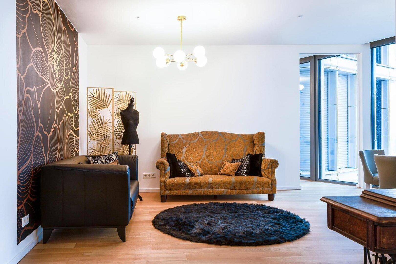 Elegantes Wohnzimmer mit dunklem Sofa, gemusterter Tapete und hellem Holzboden.