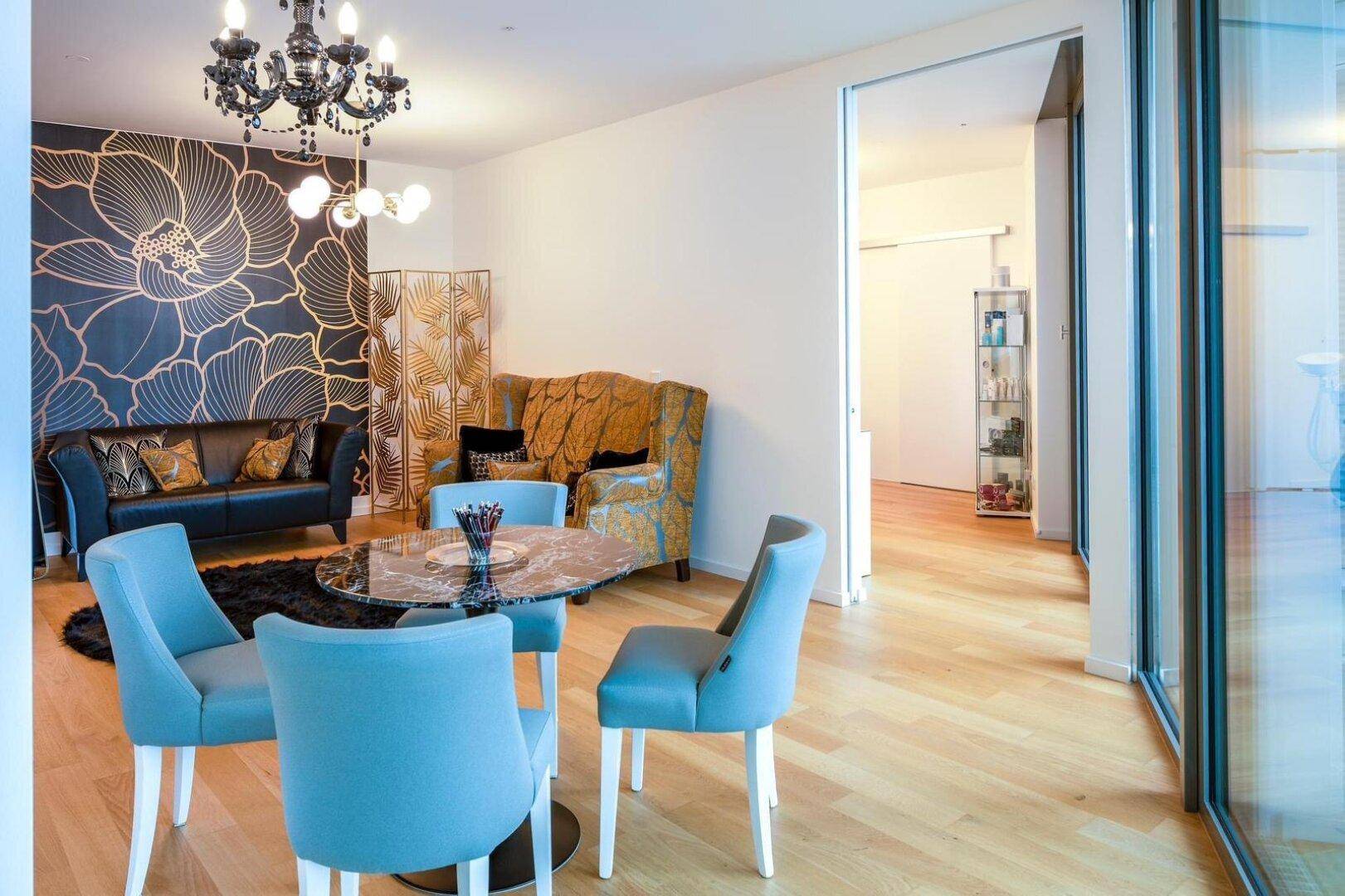 Stilvolles Wohnzimmer mit auffälliger Tapete, bequemen Sofas und modernem Kronleuchter.