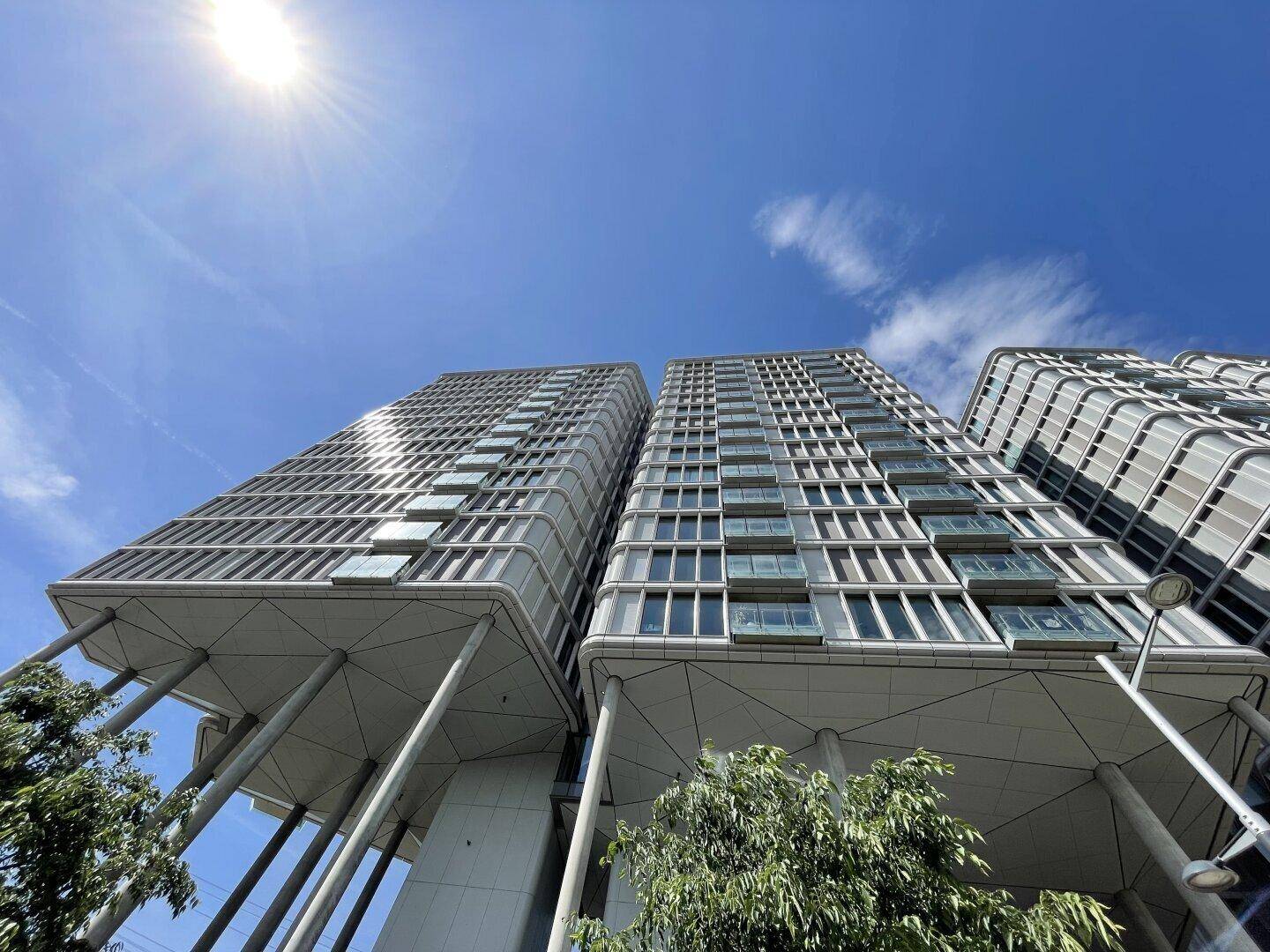 Moderne Hochhäuser mit einzigartiger Architektur und vielen Fenstern unter blauem Himmel.