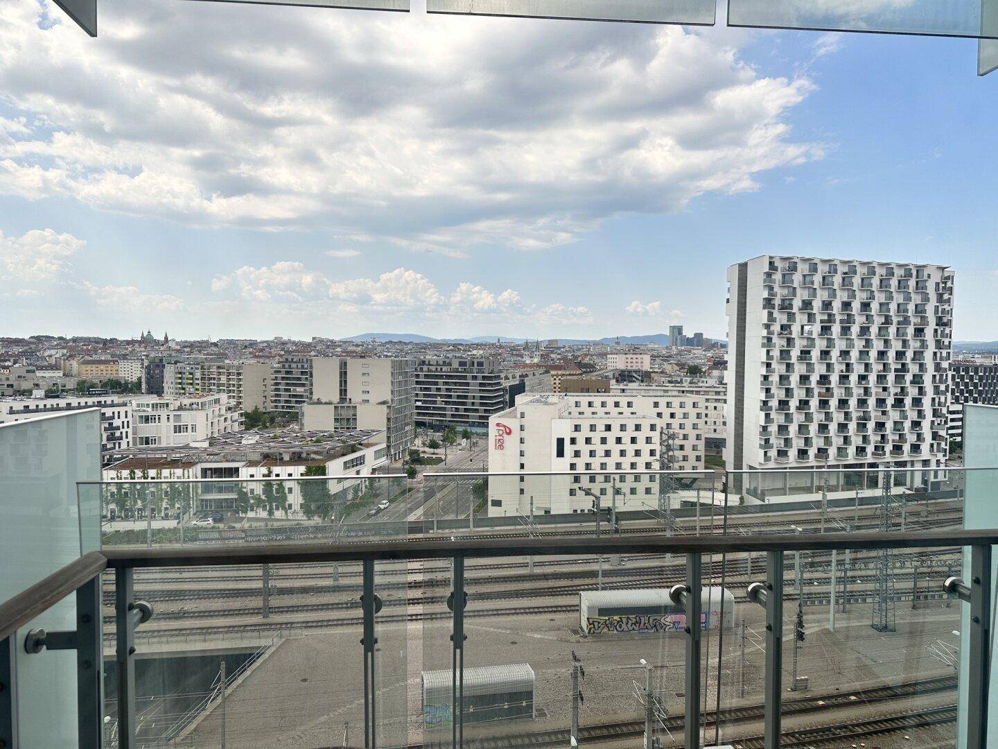 Balkon mit Glasgeländer bietet einen weiten Blick über die Stadt und Bahngleise.