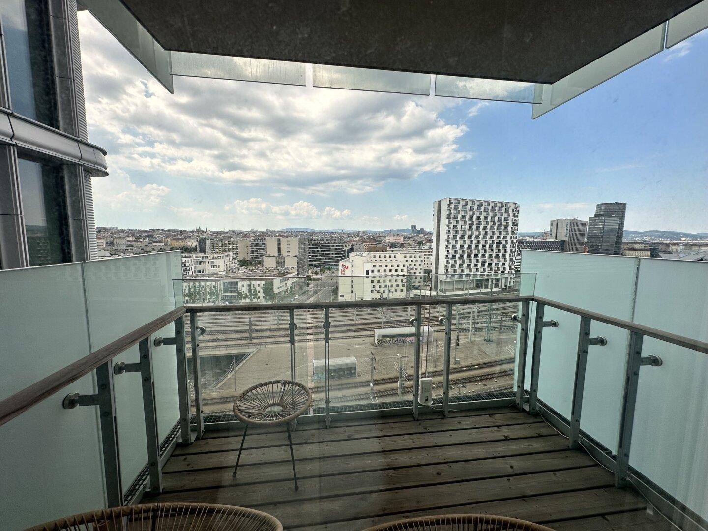 Balkon mit Holzboden und Glasgeländer bietet einen weiten Blick über die Stadt.