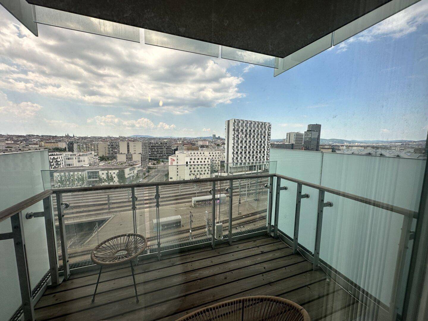 Balkon mit Holzboden und Glasgeländer bietet einen weiten Blick über die Stadt.