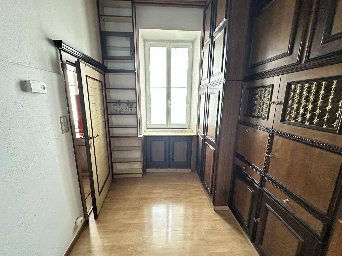 Schmaler Raum mit vielen Einbauschränken und Regalen, ideal als Ankleide oder Abstellraum.