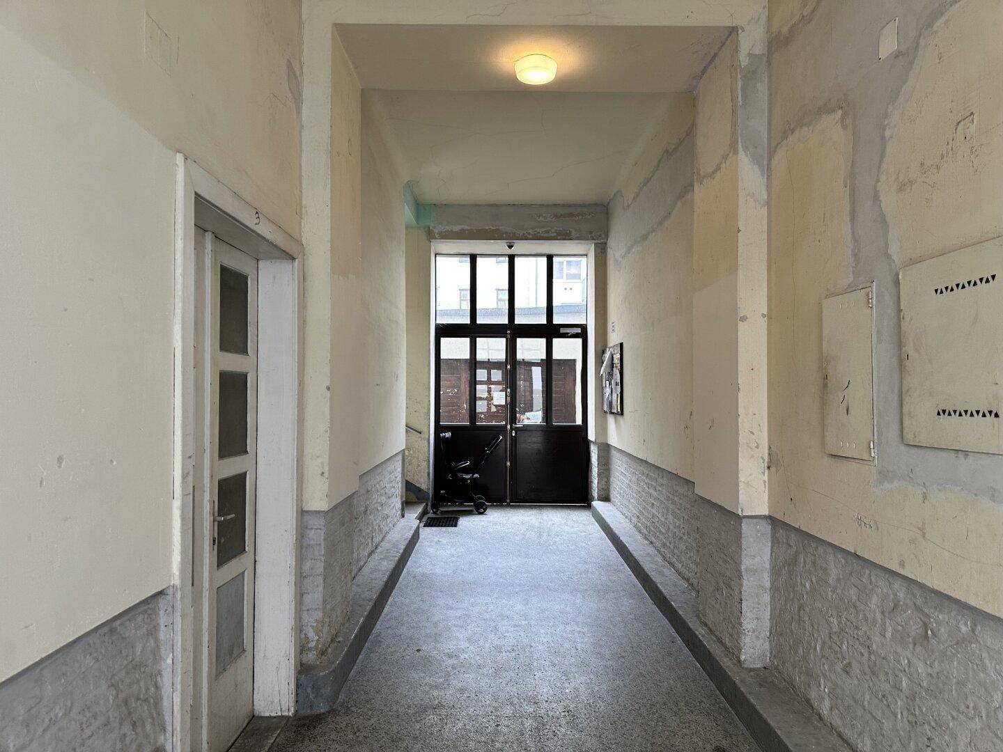 Eingangsbereich eines Mehrfamilienhauses mit langen Fluren und Zugangstüren.