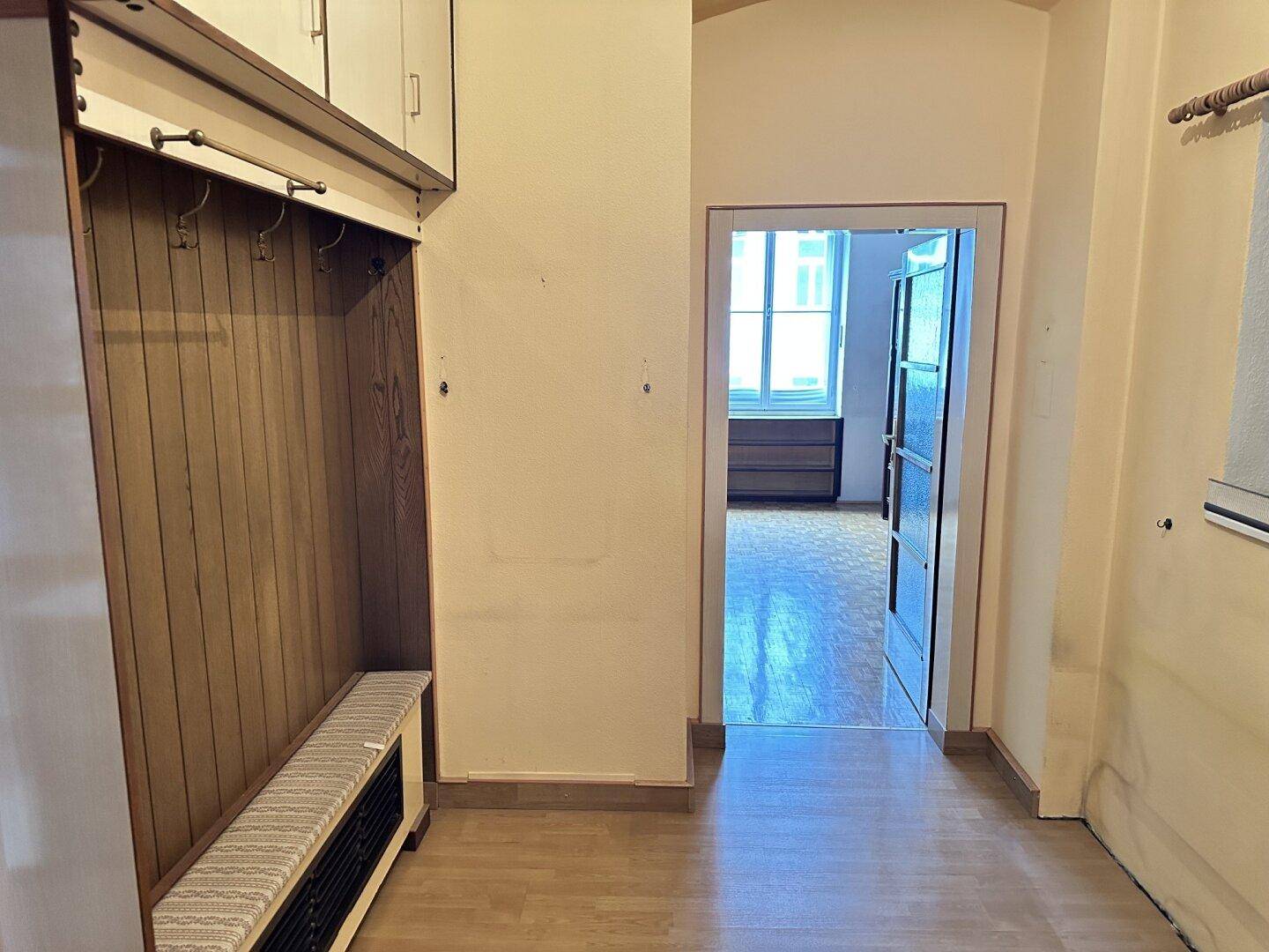 Eingangsbereich mit integrierter Garderobe und Sitzbank, führt zu einem weiteren Zimmer.
