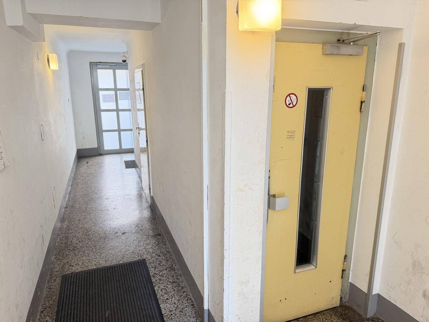 Heller Hausflur mit Terrazzoboden und Zugang zu einem weiteren Bereich.