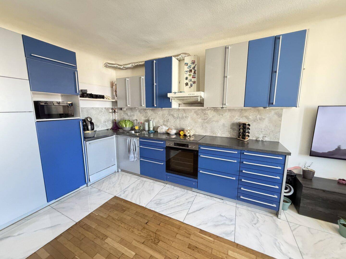 Funktionale Küche mit blauen und weißen Schränken, integriertem Backofen und Geschirrspüler.