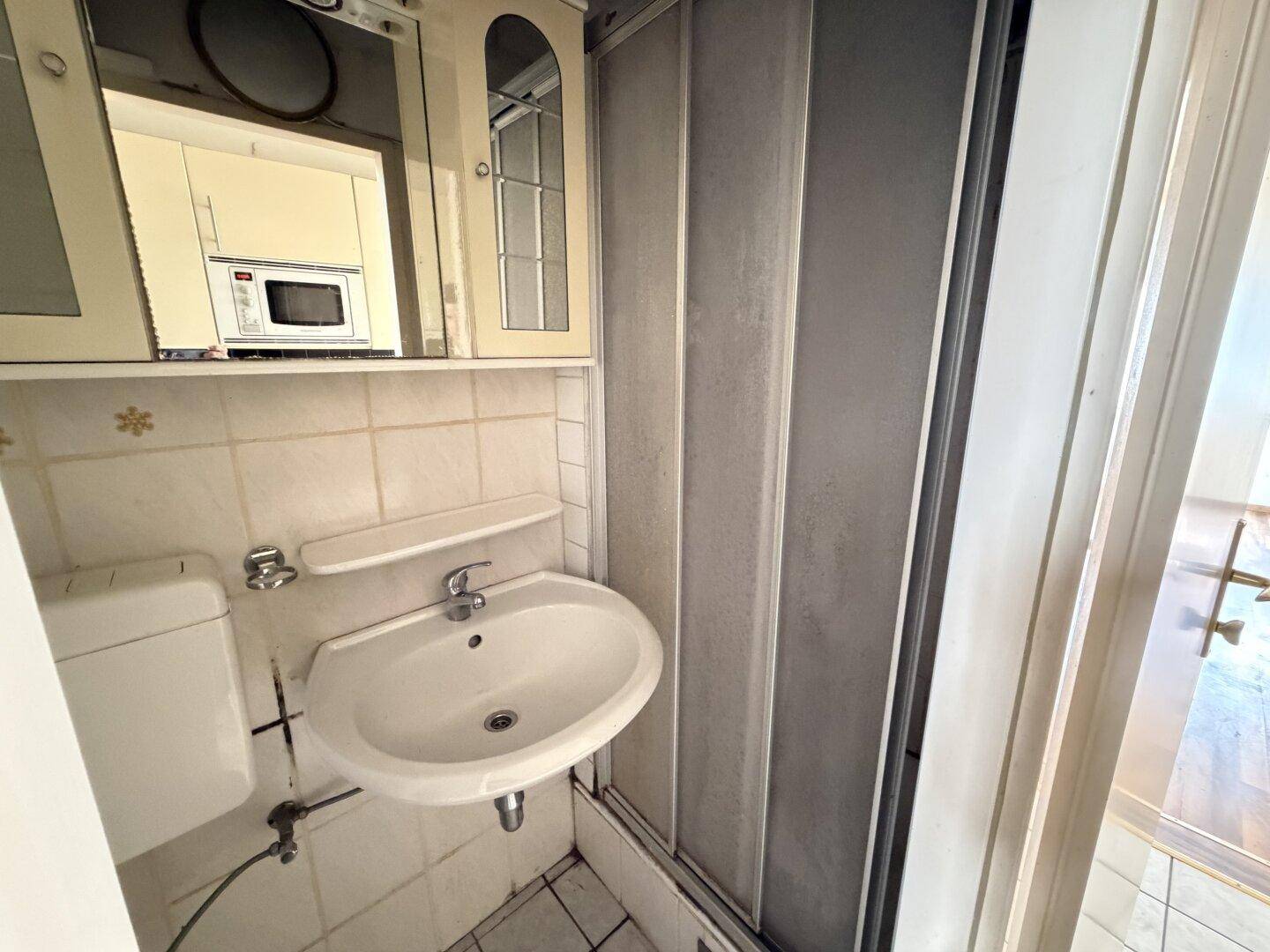 Kompaktes Badezimmer mit Duschkabine, Waschbecken und Spiegelschrank, funktional eingerichtet.