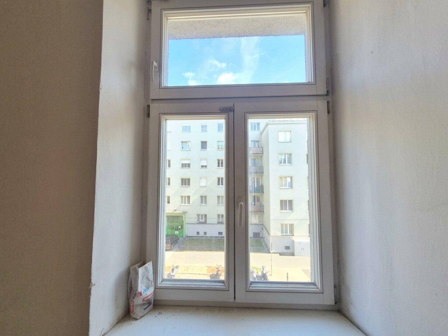 Fenster mit Blick auf den Innenhof und umliegende Gebäude, bietet natürliches Licht.
