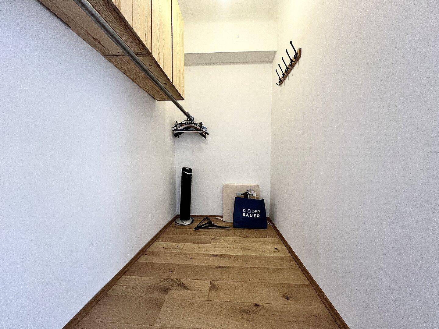 Praktischer Abstellraum mit Holzboden, Regal und Garderobenhaken für zusätzlichen Stauraum.