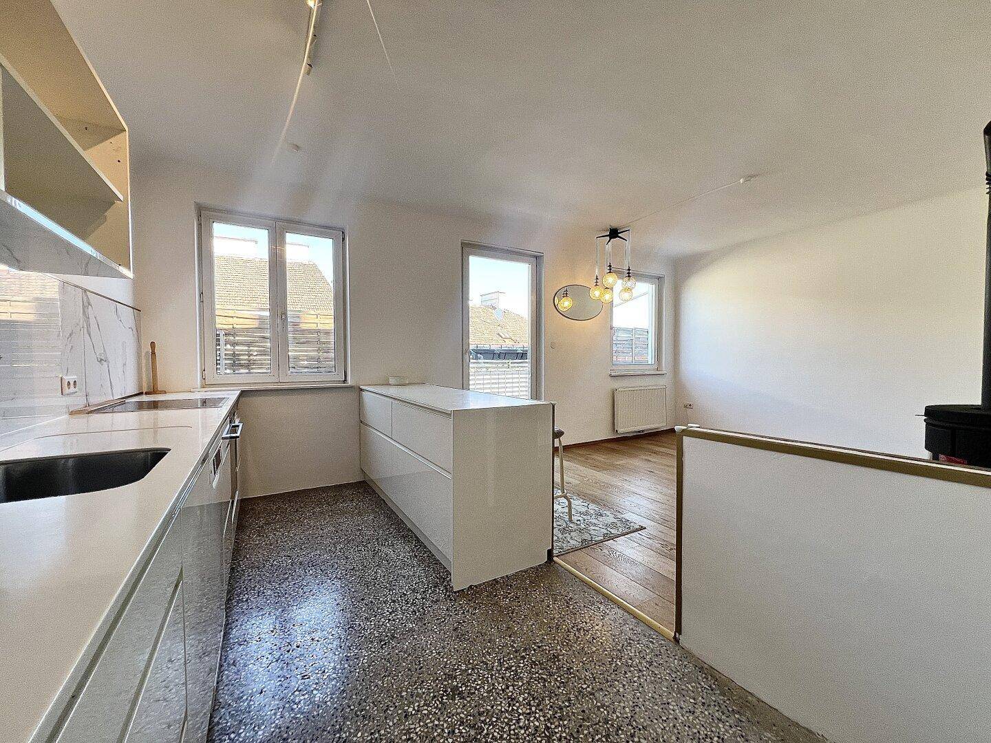 Moderne Küche mit Kücheninsel und Terrazzoboden, offen zum Wohnbereich gestaltet.