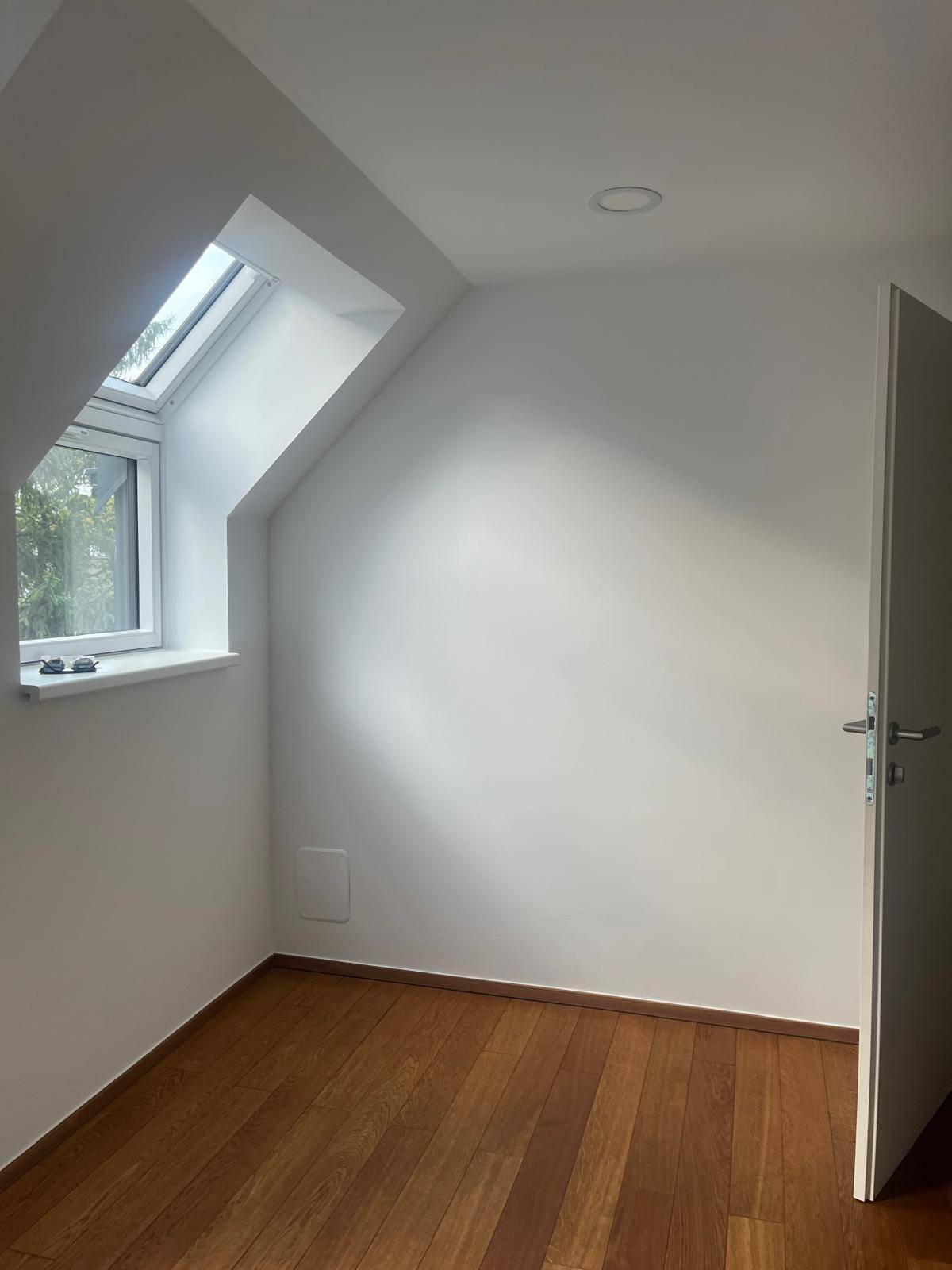 Kleiner Raum mit Holzboden und Dachfenster, ideal als Abstellraum oder Büro.