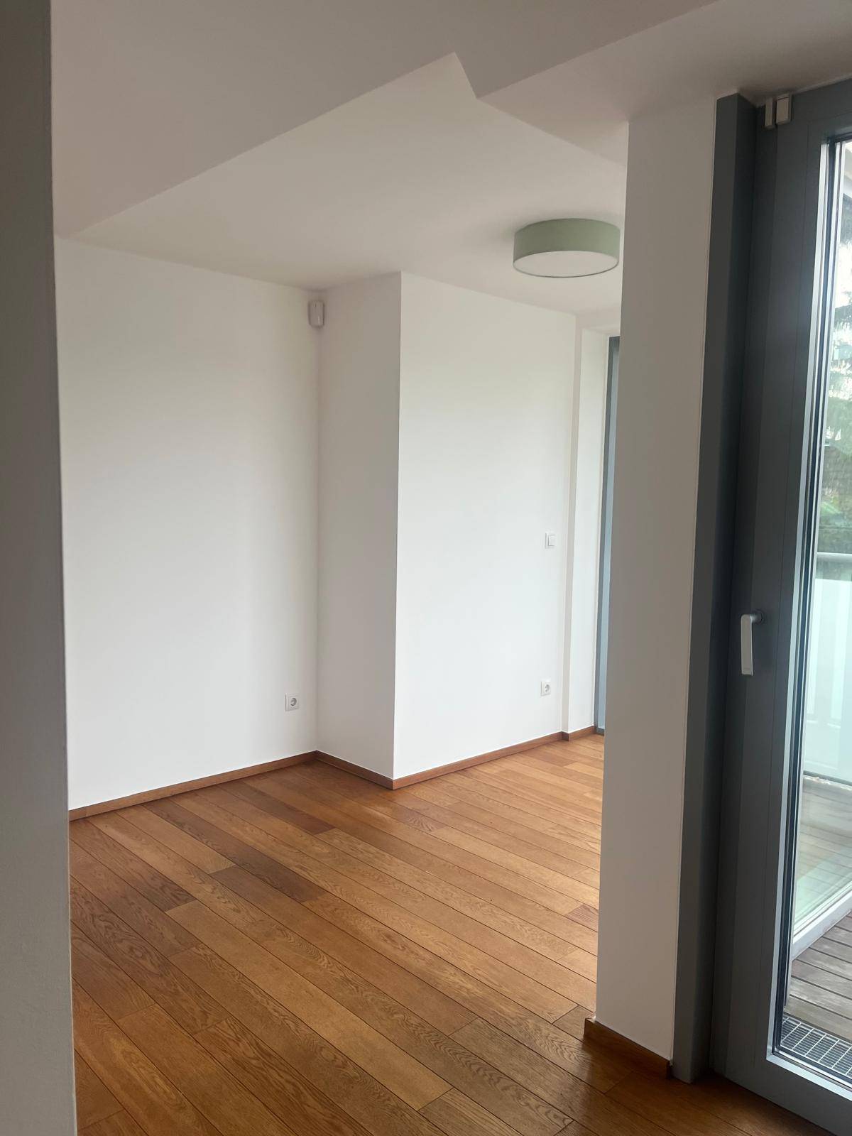 Heller, leerer Raum mit Holzboden und weißen Wänden, bereit zur Einrichtung.