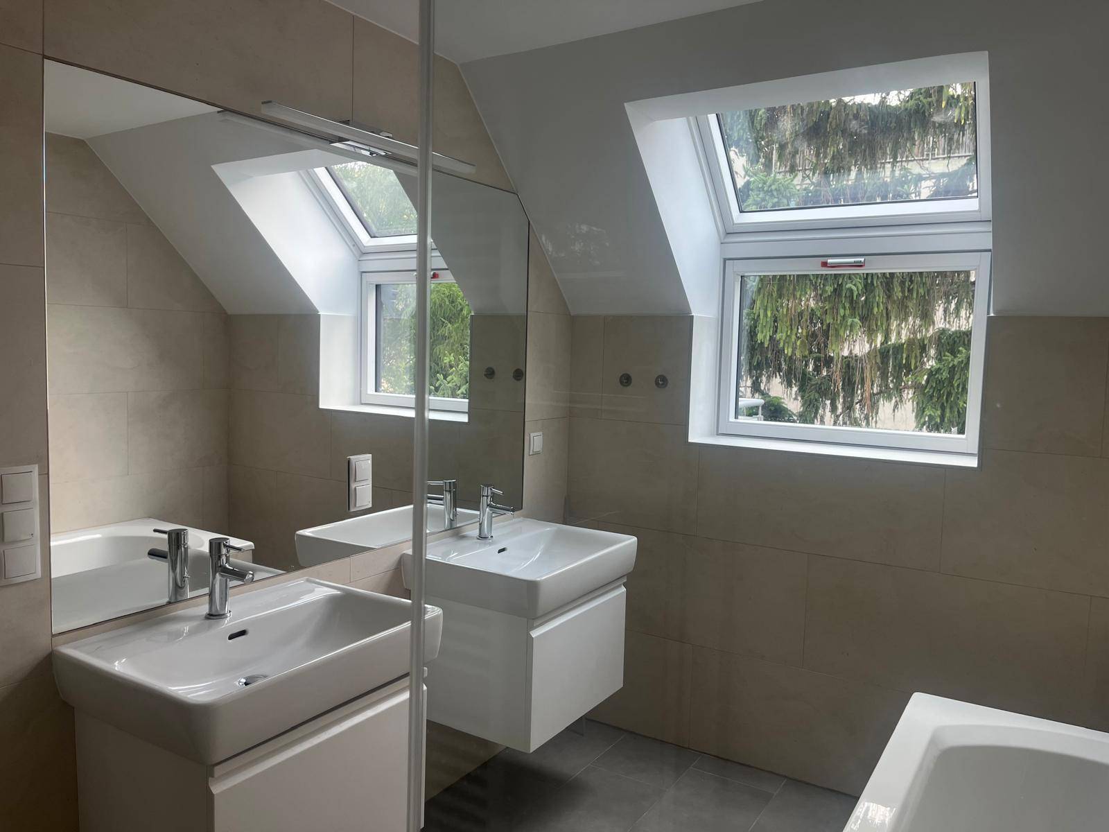 Modernes Badezimmer mit Doppelwaschbecken, großem Spiegel und Dachfenstern.
