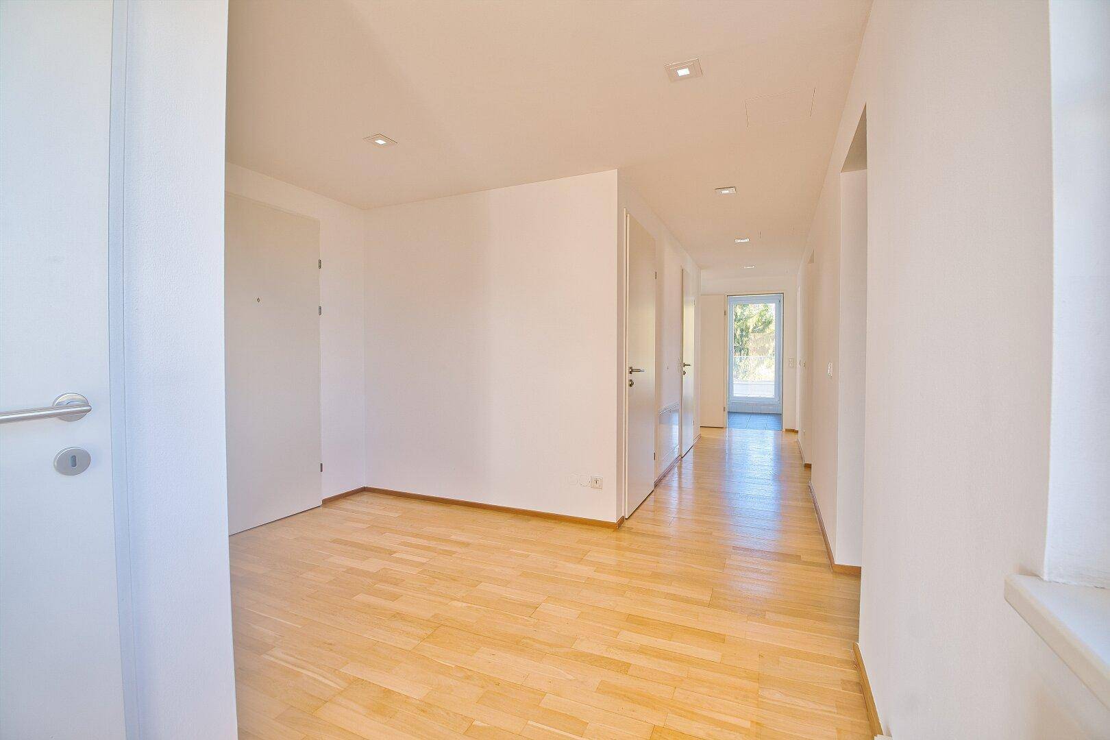 Heller Flur mit Parkettboden und Einbauschränken, führt zu weiteren Räumen der Wohnung.