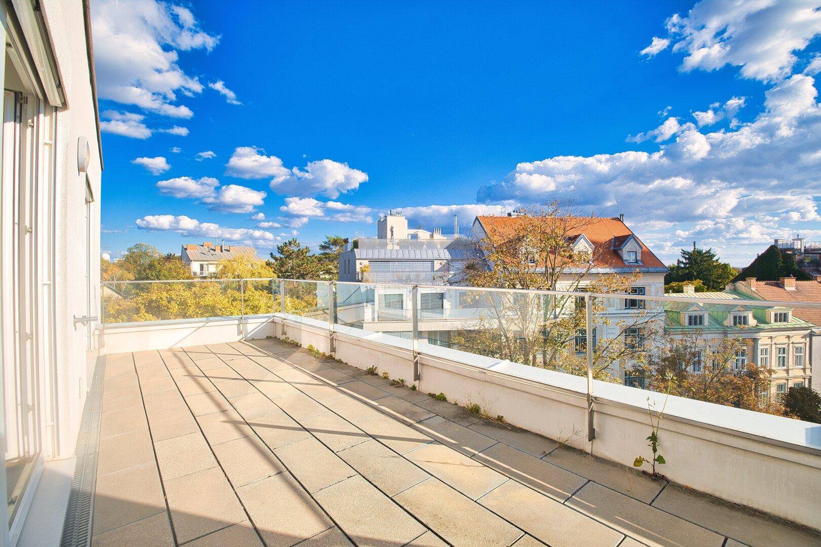Geräumige Dachterrasse mit Glasgeländer und weitem Blick über die Stadt und die Umgebung.