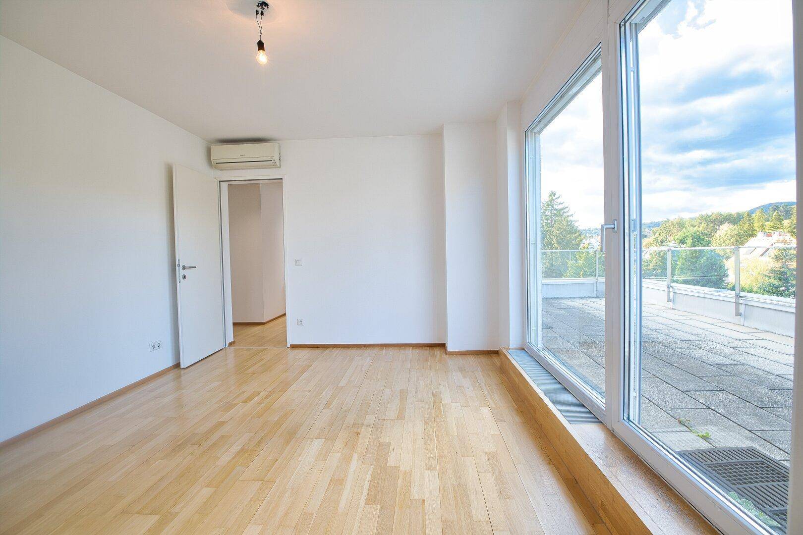 Geräumiges Schlafzimmer mit Parkettboden, Klimaanlage und direktem Zugang zur Terrasse.