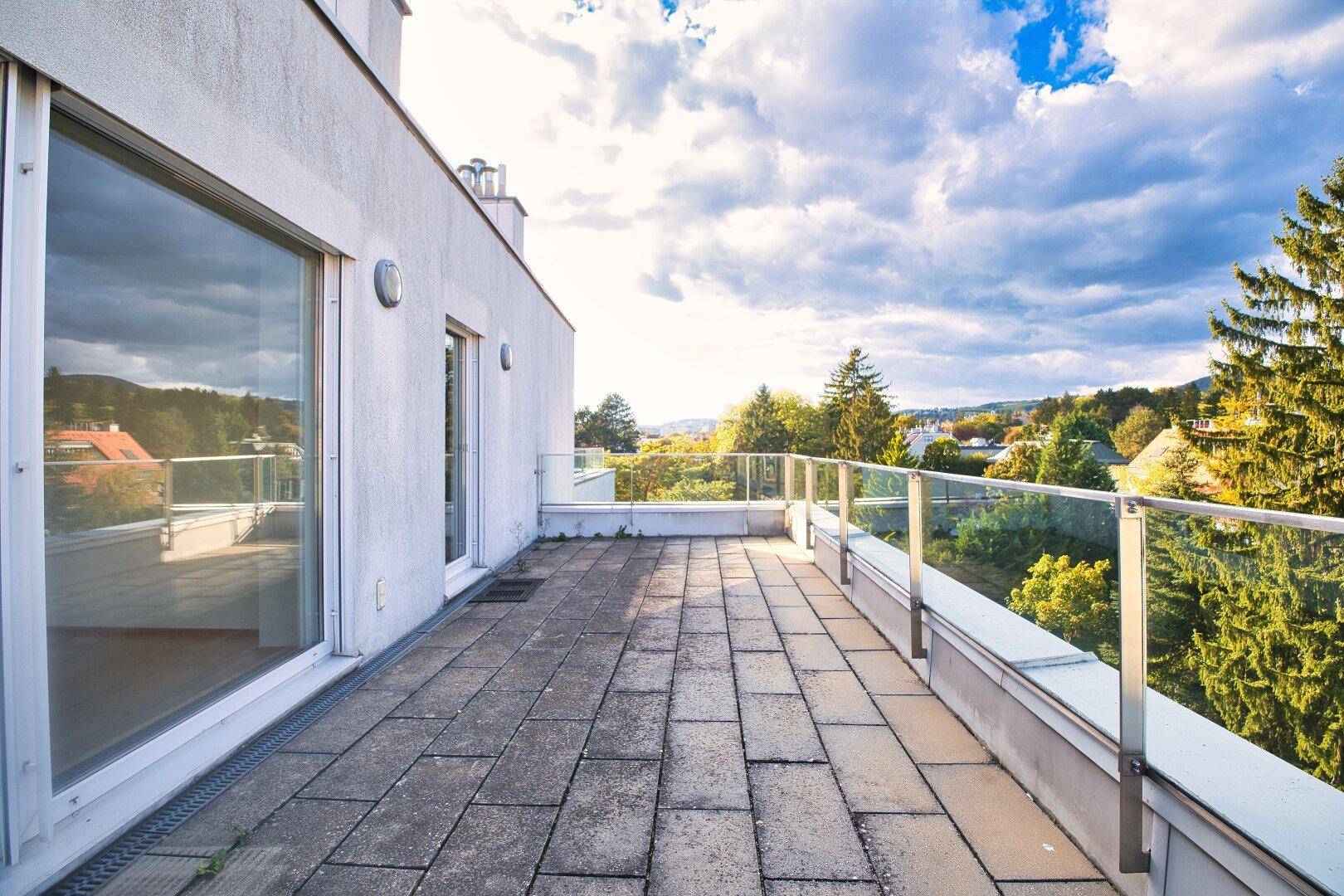 Weitläufige Terrasse mit Blick auf die grüne Umgebung und den blauen Himmel, ideal zum Entspannen.