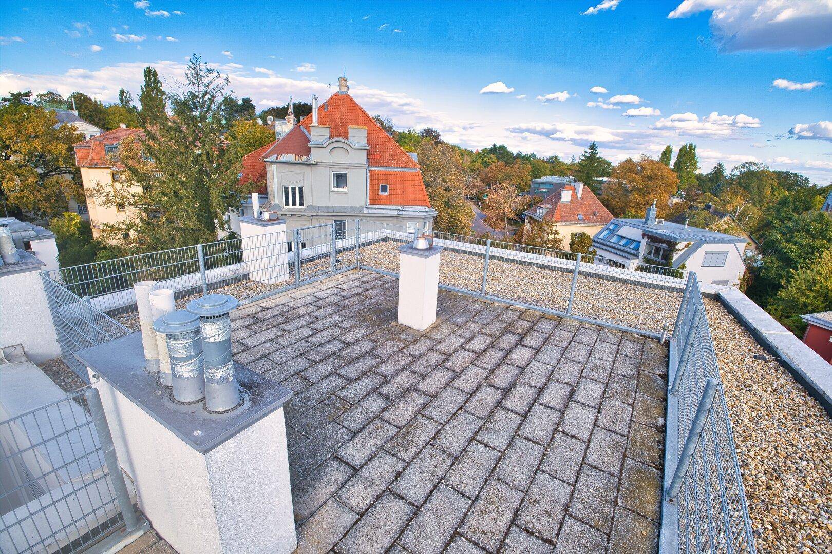 Dachbereich mit Kiesbelag und Blick auf die umliegenden Gebäude und die grüne Landschaft.