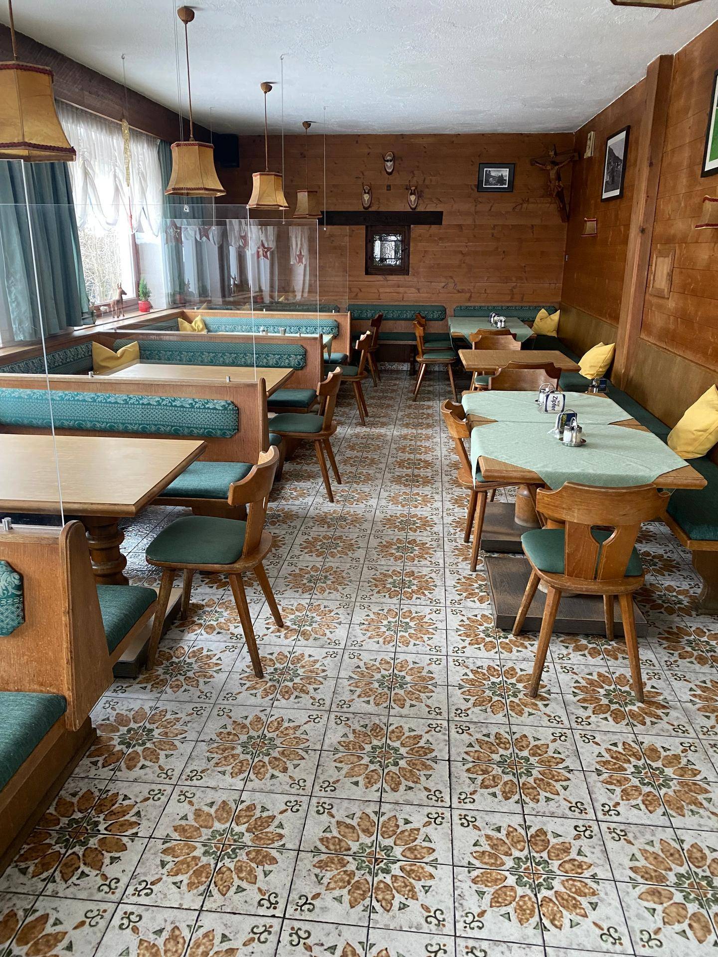 Rustikaler Speisesaal mit Holztäfelung, gemusterten Fliesen und traditionellen Sitzgelegenheiten.
