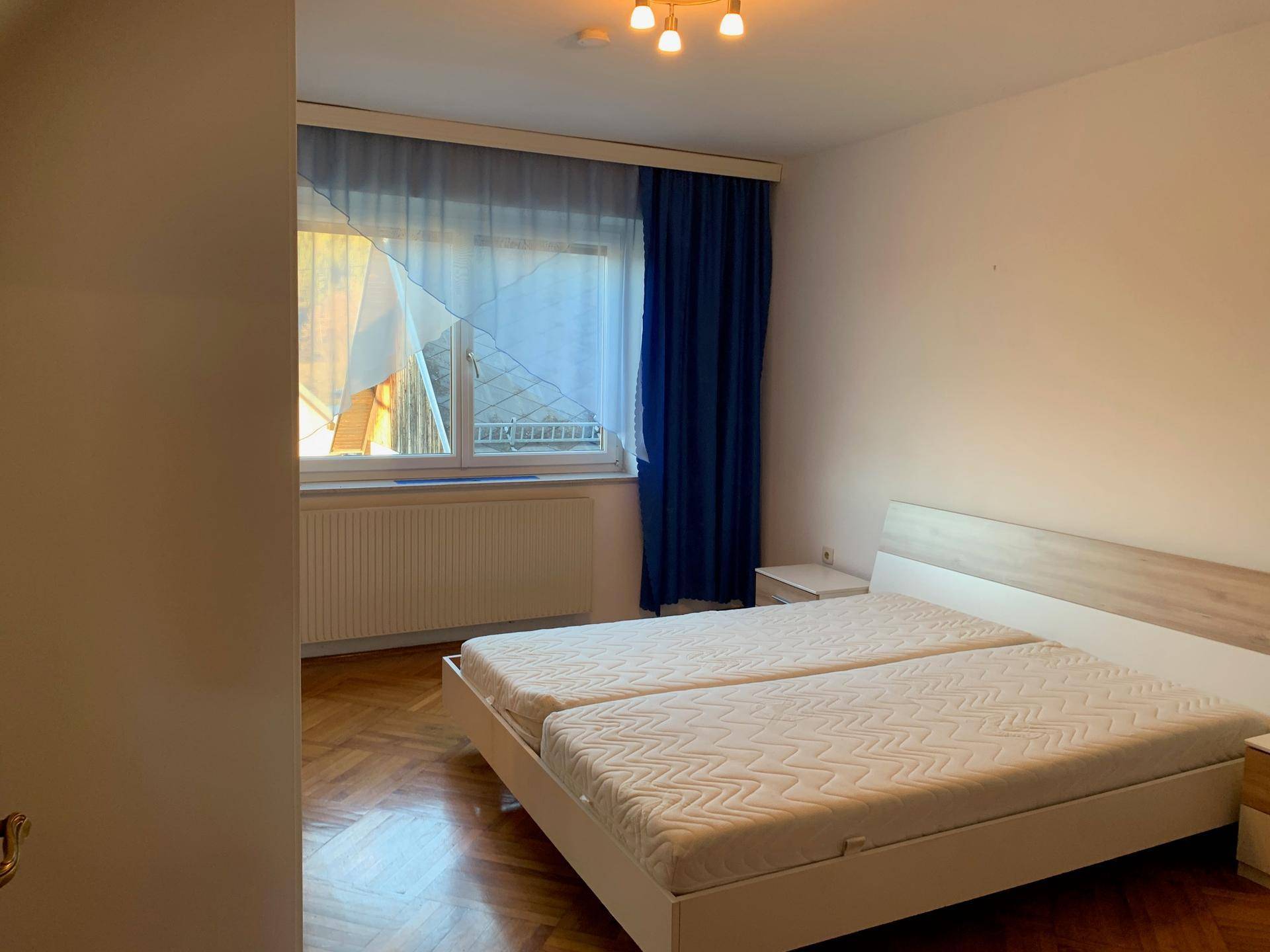 Helles Schlafzimmer mit Doppelbett, Nachttischen und einem Fenster mit Blick nach draußen.