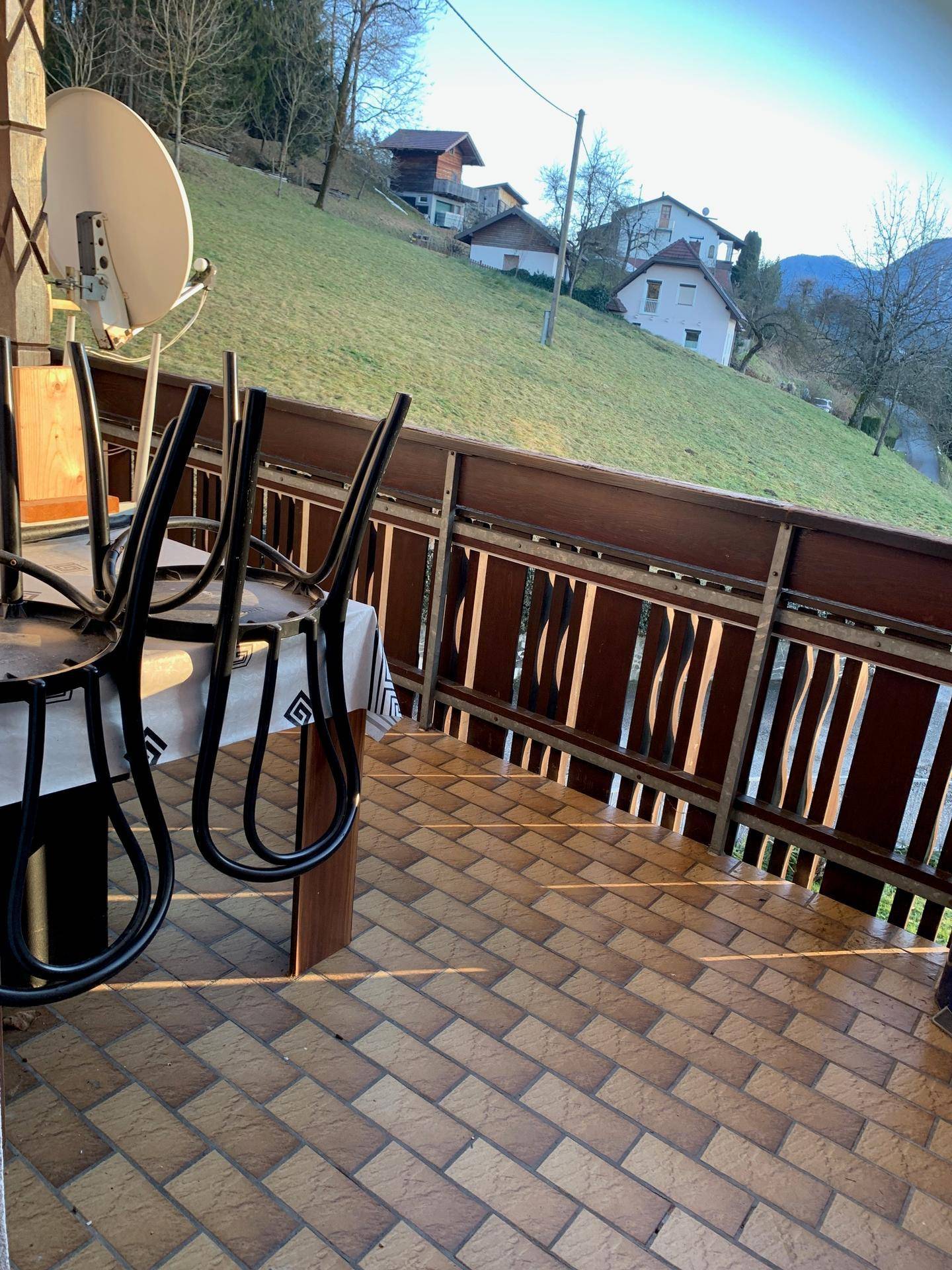Gefliester Balkon mit Holzgeländer und Blick auf die umliegende Hügellandschaft und Häuser.