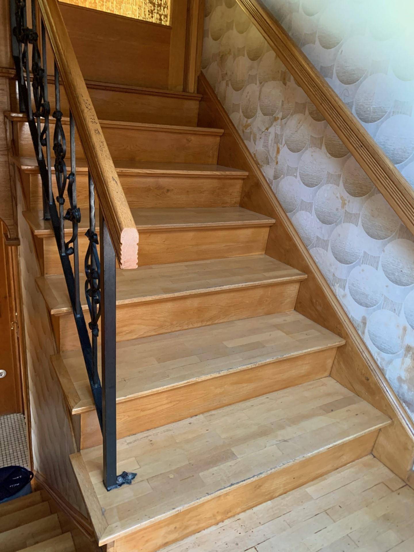 Detailansicht der Holztreppe mit dekorativem Geländer und traditioneller Wandgestaltung.