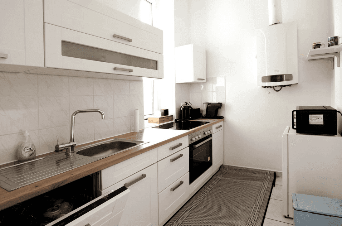 Moderne Einbauküche mit weißen Fronten, Holzdetails und praktischer Ausstattung.