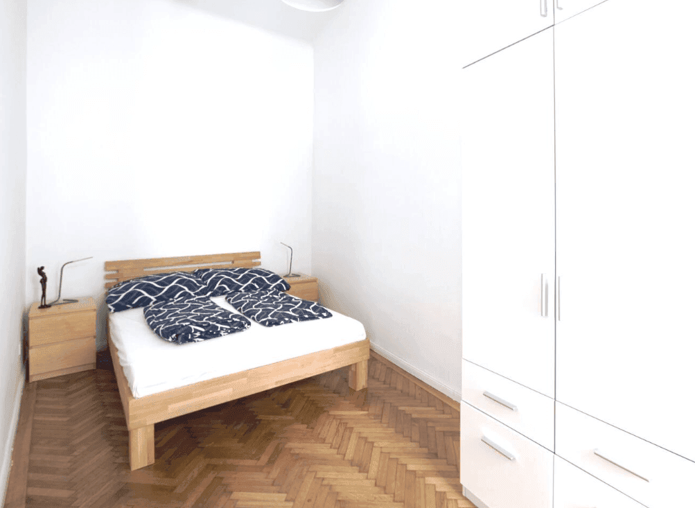 Helles Schlafzimmer mit Holzbett, Nachttischen und Parkettboden.