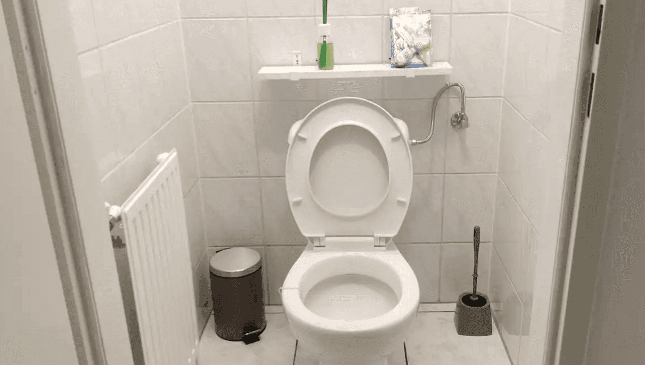 Separates WC mit Toilette, Heizung und Fliesenboden.