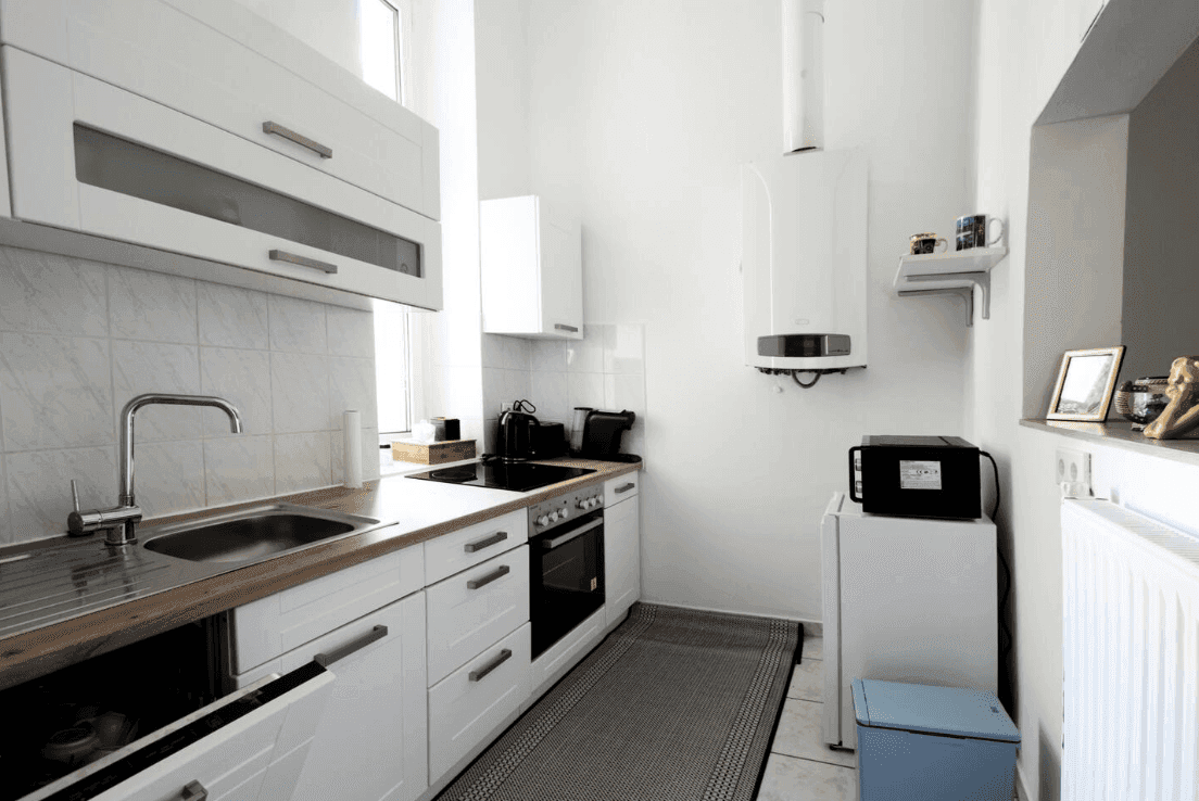 Funktionale Küche mit weißen Schränken, Holzarbeitsplatte und integrierten Geräten.