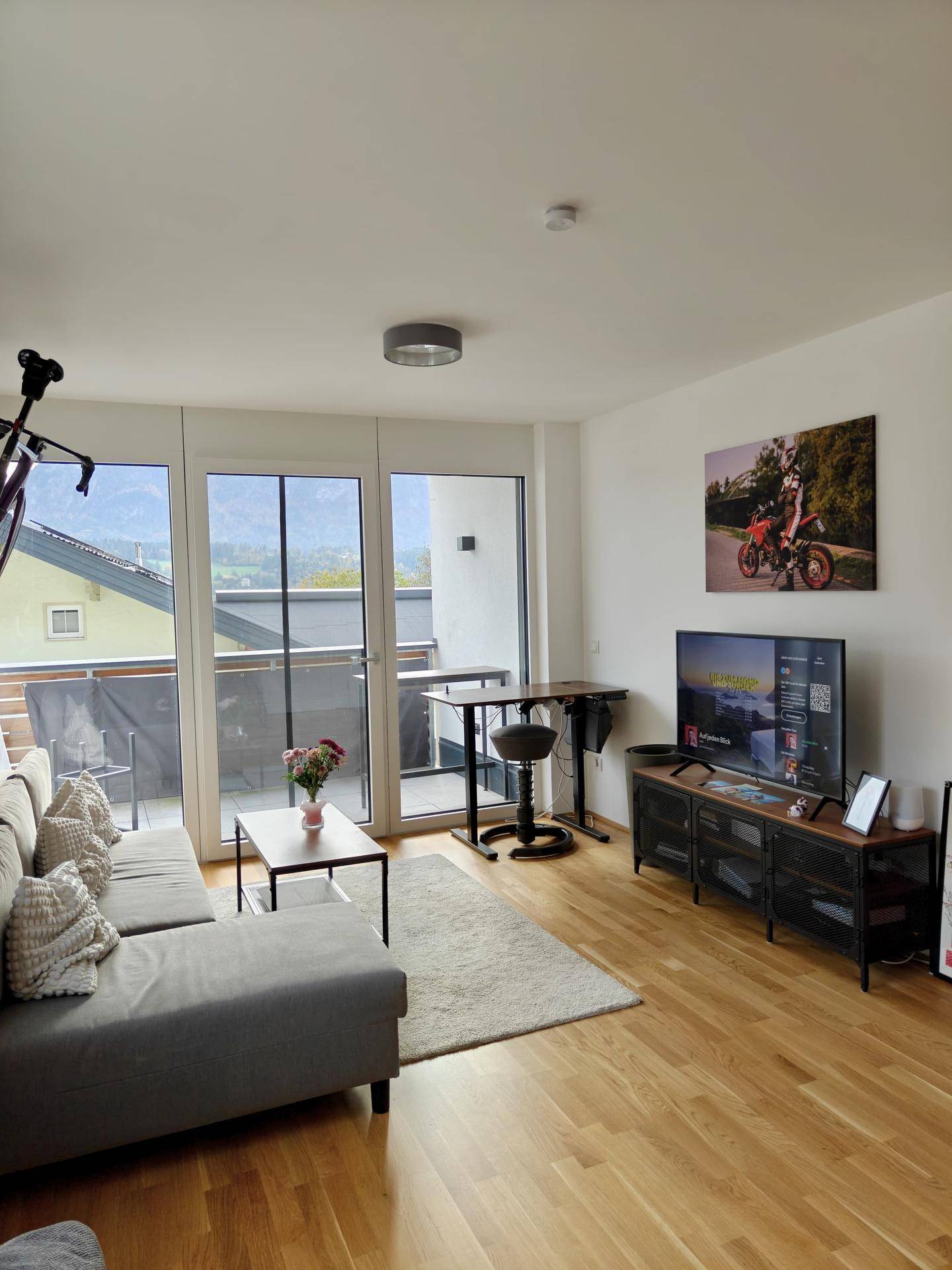 Lichtdurchflutetes Wohnzimmer mit Balkonzugang und weitem Bergblick, ideal zum Entspannen.