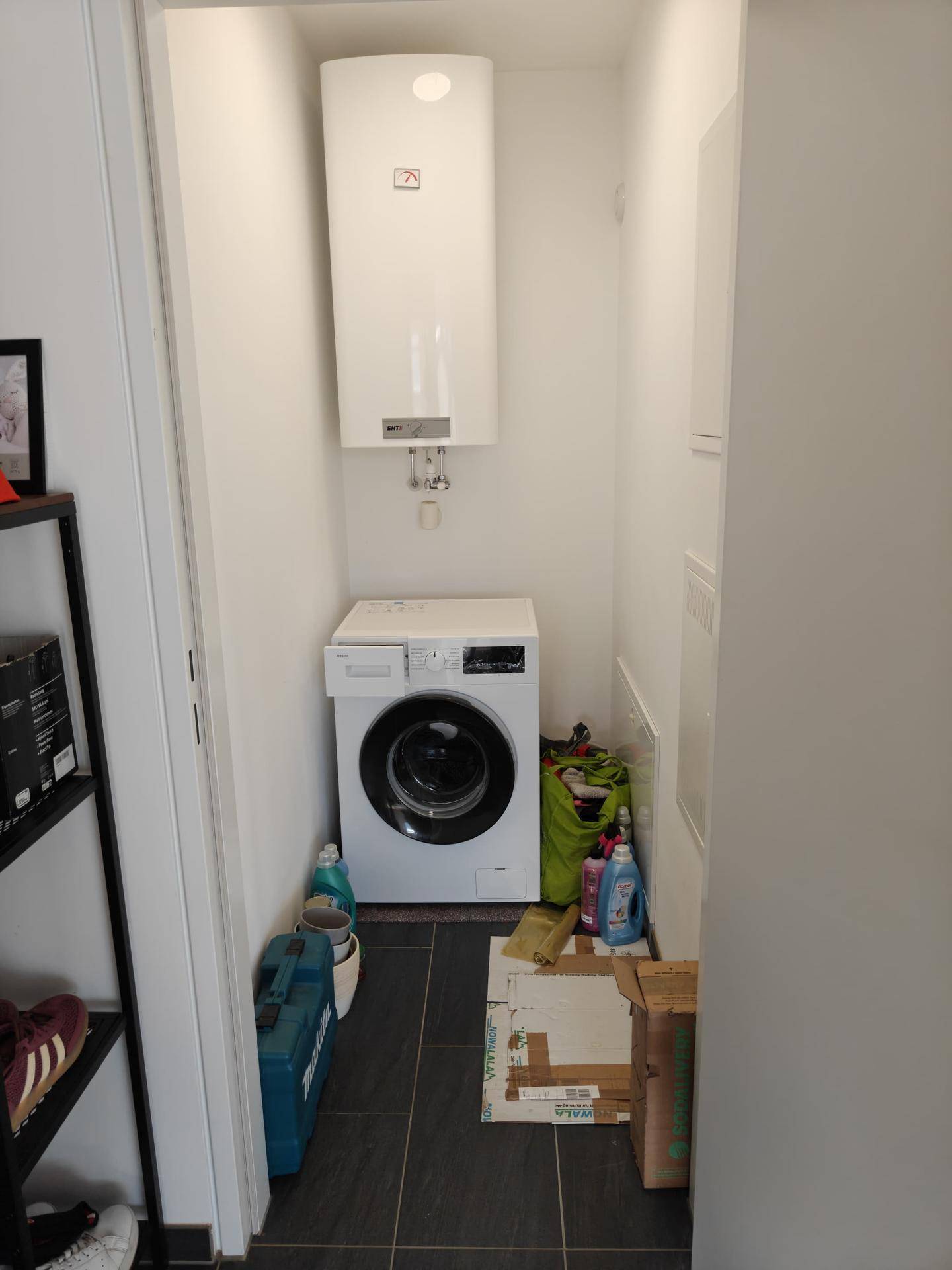 Kleiner Hauswirtschaftsraum mit Waschmaschine und Warmwasserbereiter, praktisch und funktional gestaltet.