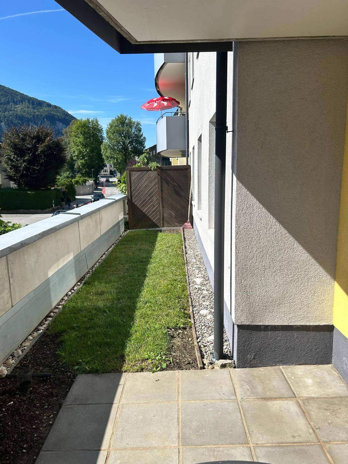 Außenbereich mit Rasenstreifen neben der Terrasse und Blick auf die umliegende Berglandschaft.