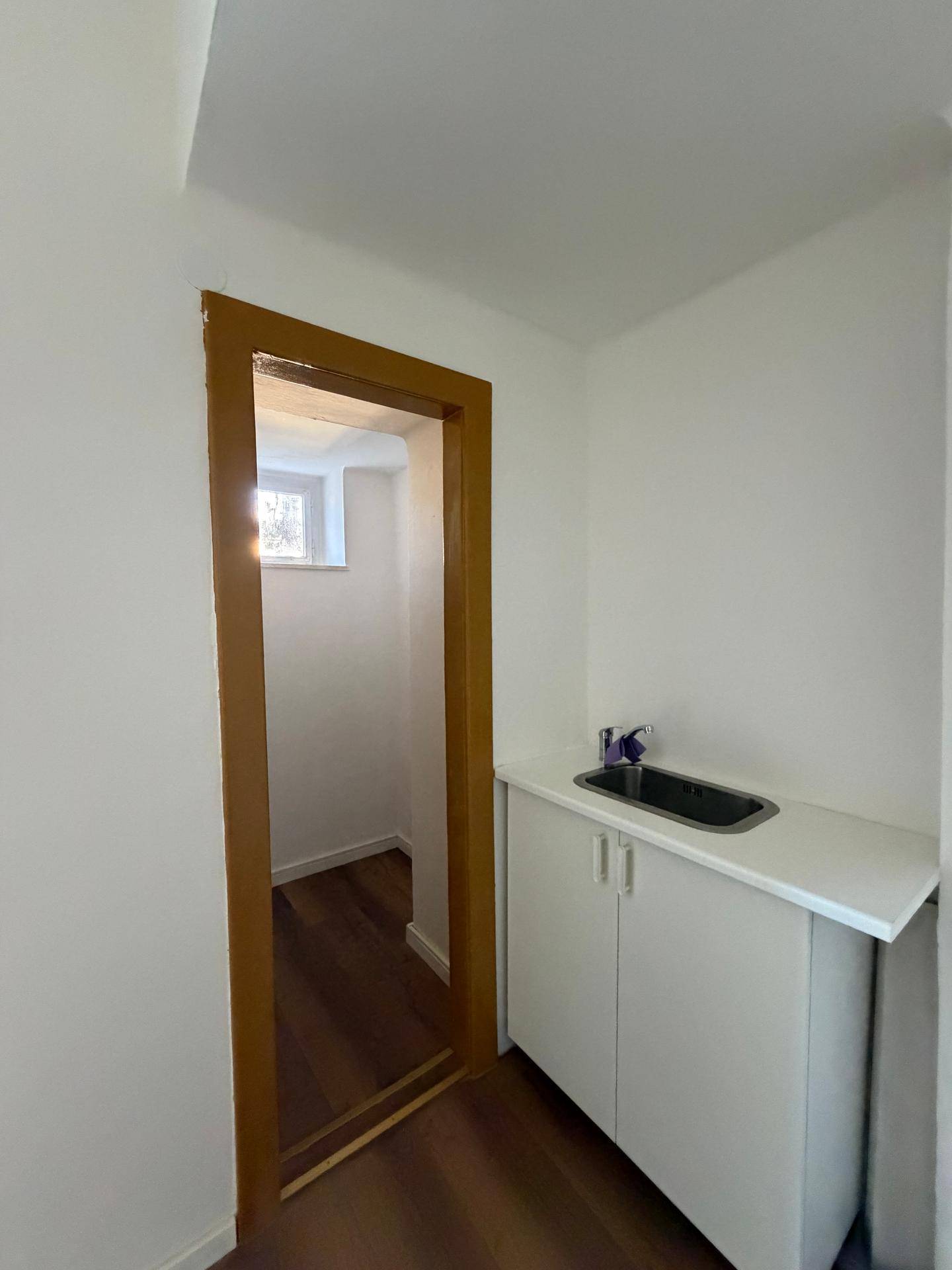 Praktischer Hauswirtschaftsraum mit Spülbecken und Unterschrank, ideal für zusätzliche Lagerung.