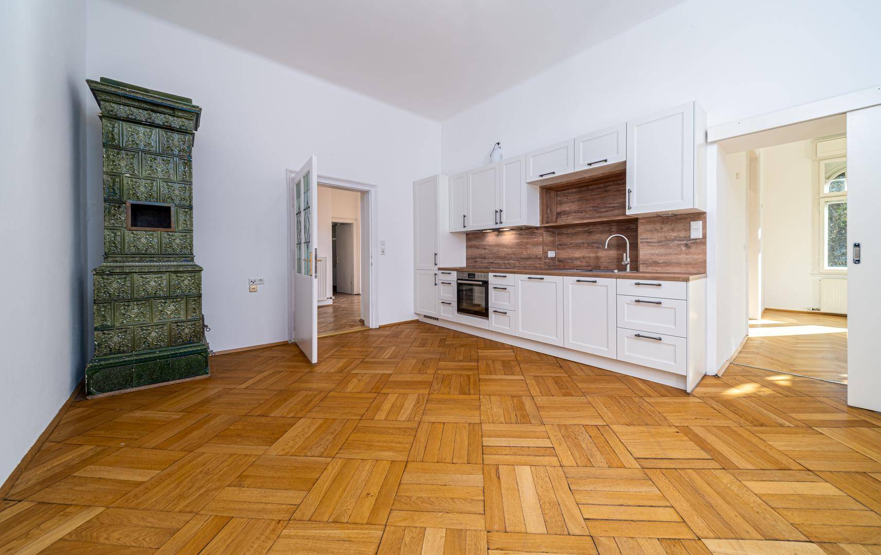 Helle Küche mit Einbauküche, Kachelofen und Parkettboden.