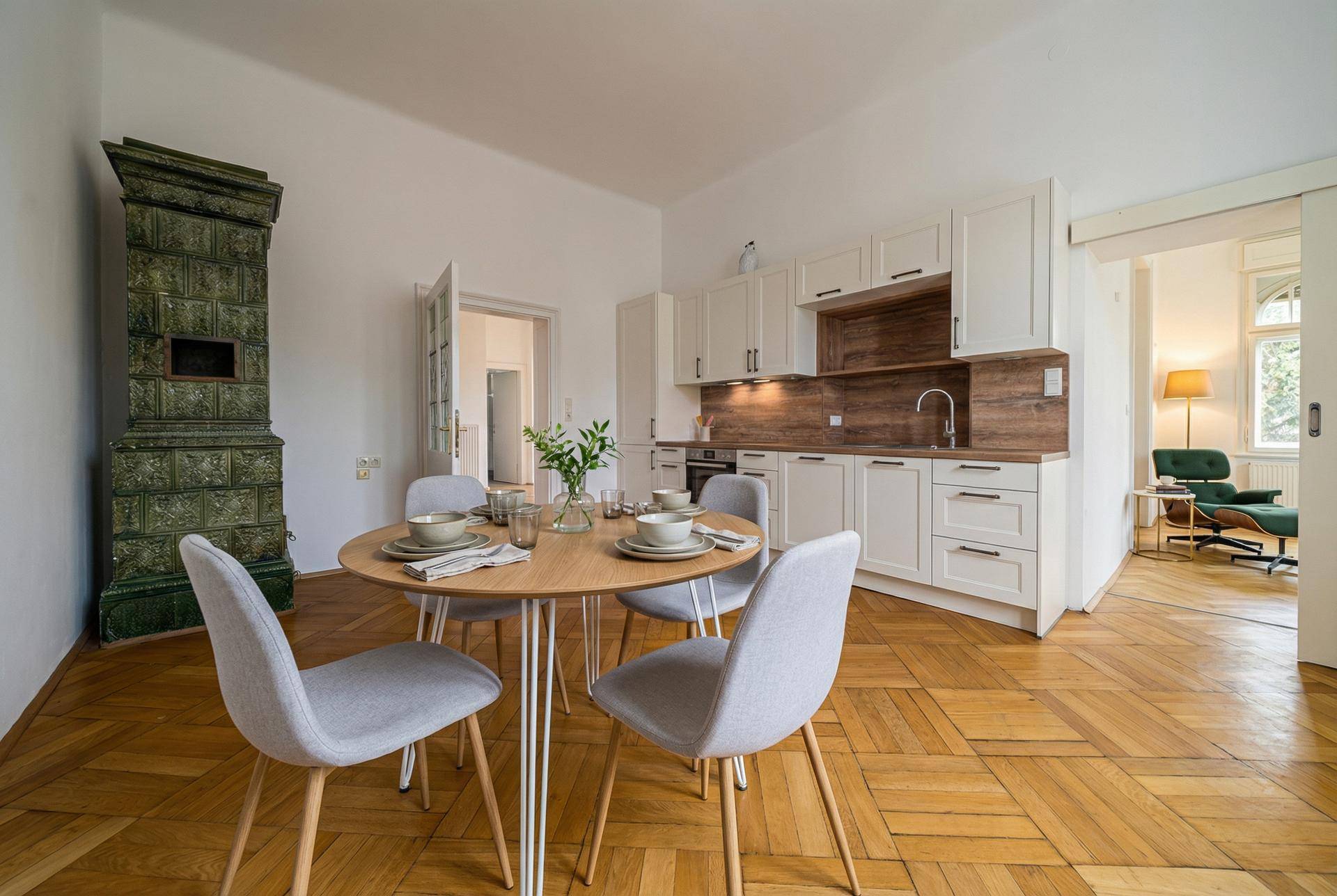 Moderne Küche mit Essbereich, Kachelofen und Parkettboden.