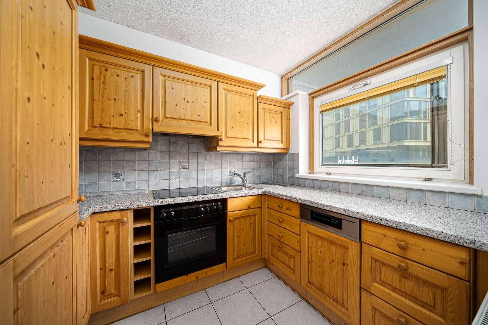 Traditionelle Holzküche mit Granitarbeitsplatten, Fliesenboden und integrierten Geräten.