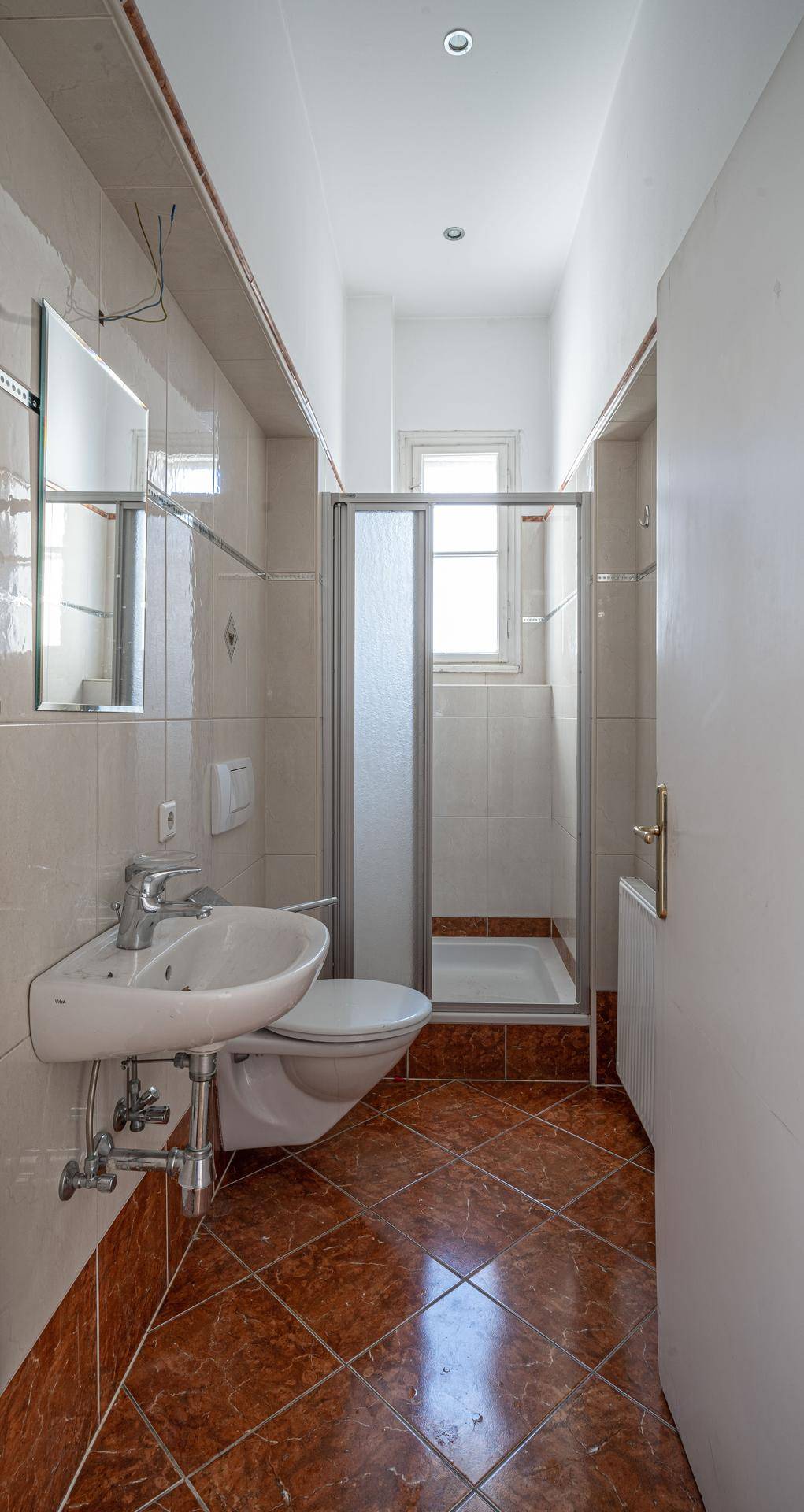 Kleines Badezimmer mit Dusche, WC und Fenster.