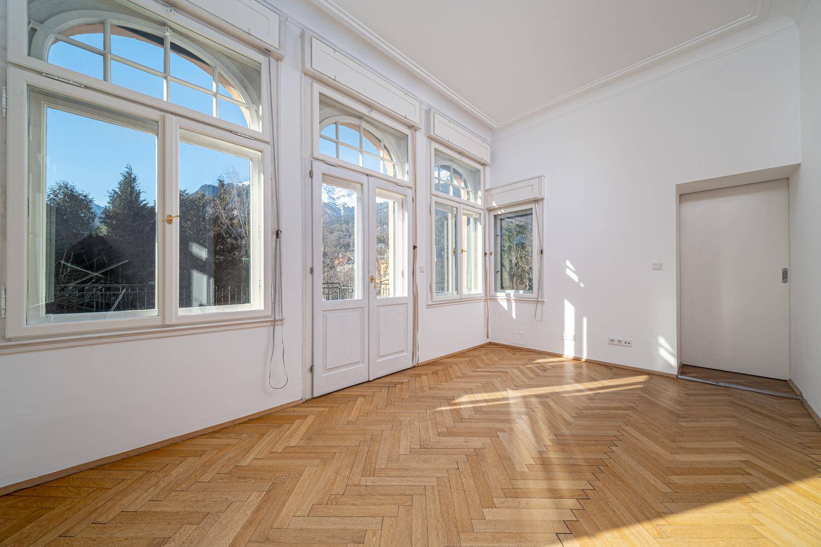 Geräumiger Essbereich mit Parkettboden und hohen Fenstern, die den Raum erhellen.