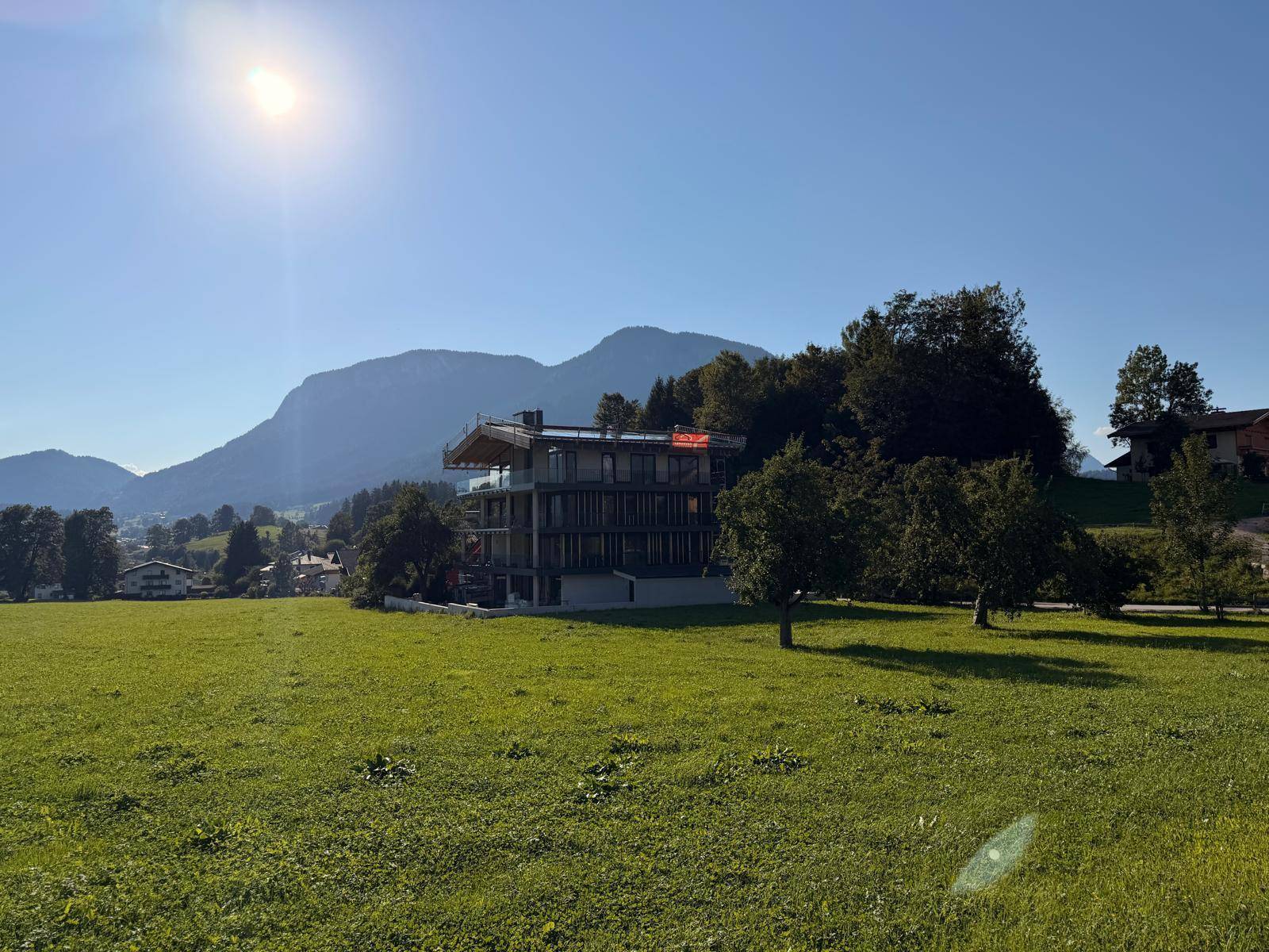 Sonnenverwöhntes Neubauprojekt in alpiner Landschaft mit weitem Blick über grüne Wiesen und Berge.